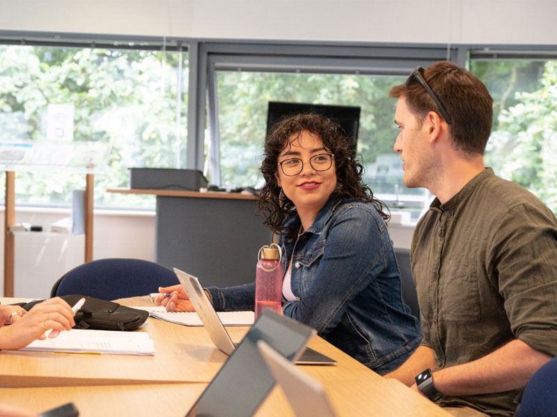 a female and male postgraduate student working together in a classroom setting