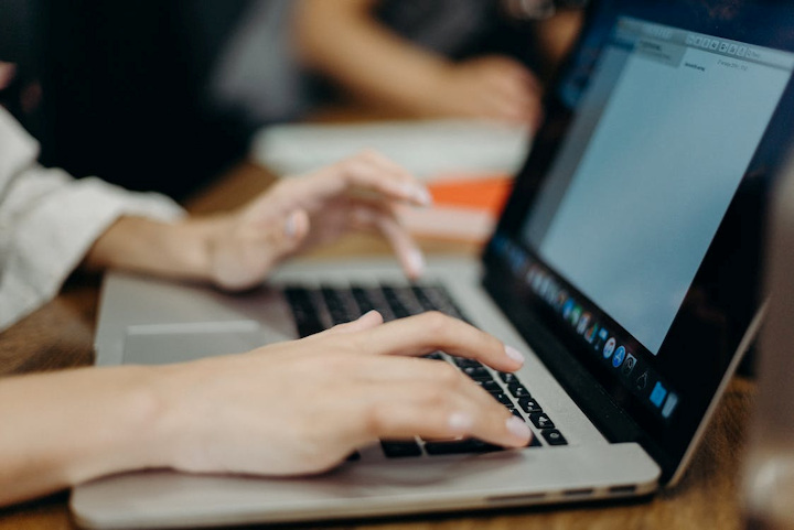 Hands typing on a laptop keyboard