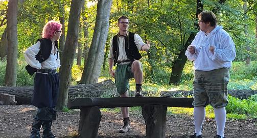 Three actors performing the Three Desperate Men and Three Fairies in parkland setting