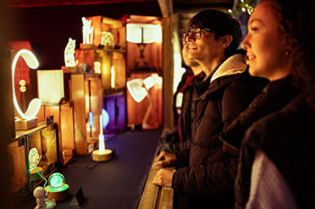 Students looking at a lit up stall in the Christmas market