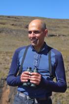 Professor Ara Monadjem holding binoculars against a mountain backdrop