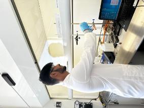 Pravardhan Hemanth Raj working in a lab, showing a test tube and a laptop